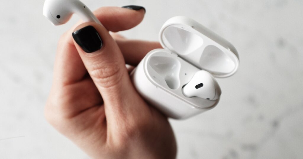 sluchawki airpods trzymane w ręku
