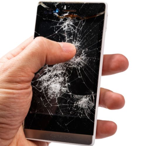 Serwisant trzyma w ręku telefon samsung ze zbitym wyświetlaczem W telefonie Samsung wymieniany jest wyświetlacz w serwisie telefonów Warszawa