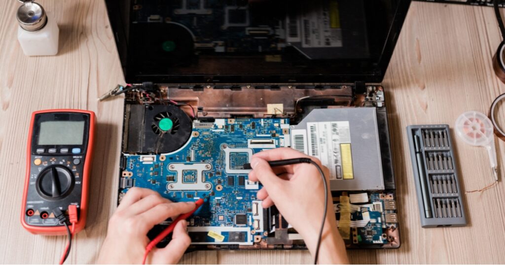serwisant naprawia laptop po zalaniu w serwisie komputerowym